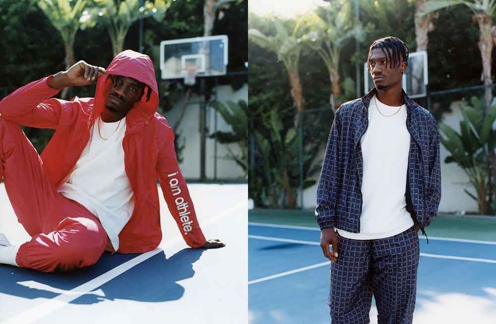 Two men are sitting on a court and one is standing up.