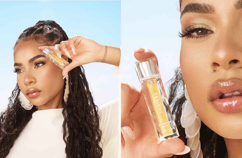 A woman putting makeup on her face and holding a bottle.