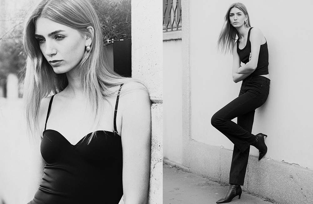 Monochrome portrait of a woman in a black dress against an urban backdrop.