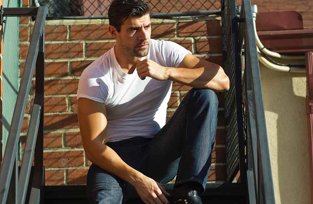 A man sitting on the ground leaning against a wall.