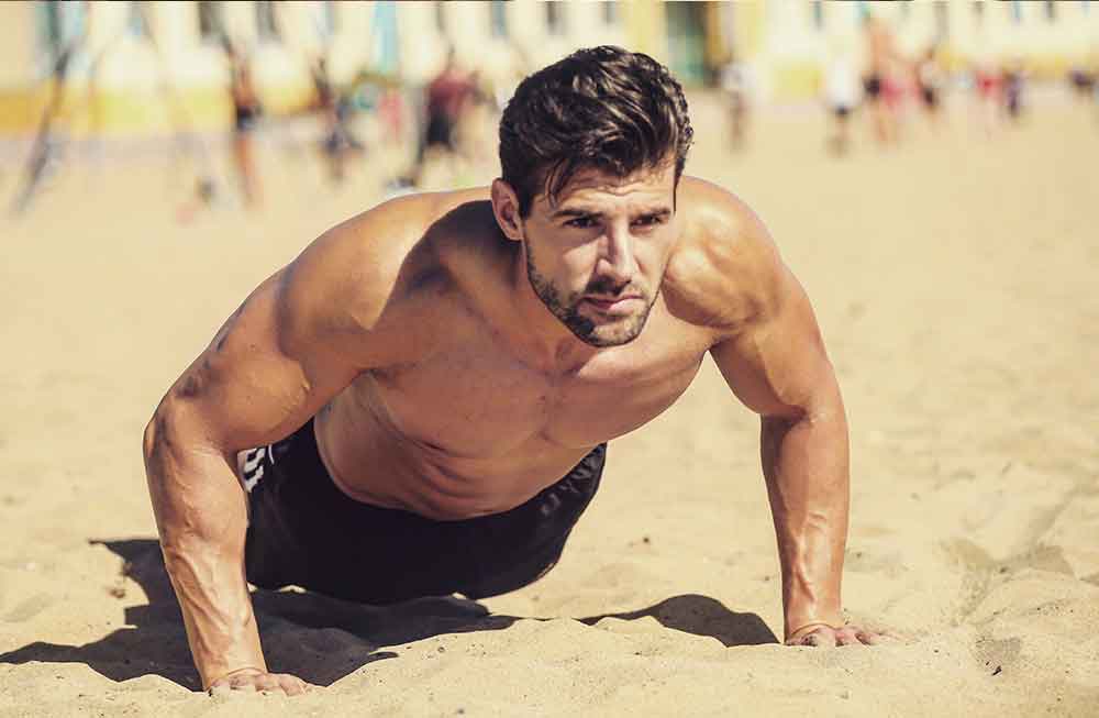 A man is doing push ups on the beach