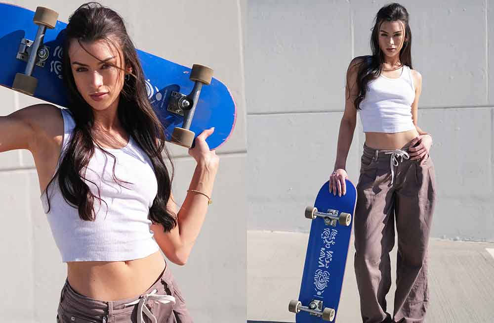 A girl holding a skateboard in front of her body.